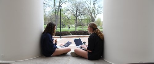 Students with laptops sitting in front of Crounse Hall